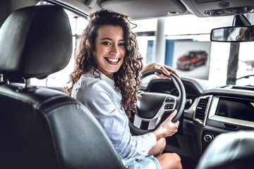 Happy woman inside car in auto show or salon