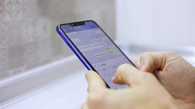 Close-up male hands holding smartphone, typing text on touch screen. Man answering friend message in social network application.