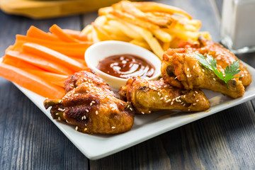 chicken wings with sesame surrounded by fries and carrots