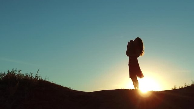 girl lifts a small dog at sunset silhouette. woman playing with a dog on nature. silute sunlight. friendship man and pet lifestyle concept