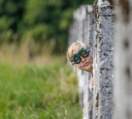 Frau mit Brille schaut seitlich hinter einer Mauer