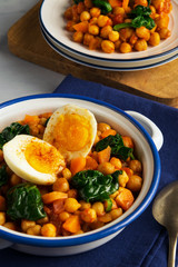 Spanish cuisine. Chickpea and spinach stew with eggs on light gray background. 