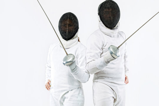 Two Young fencers athletes wearing mask and white fencing costume and holding the sword. Isolated on white background - Powered by Adobe