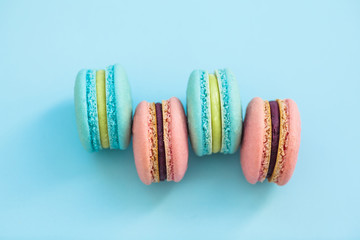 A stack of macaroons of various flavor biscuits on blue pastel background, top view. Flay lay selection of macarons.