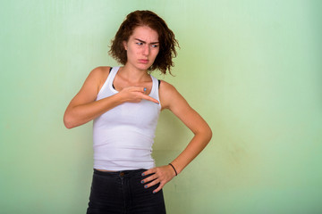 Studio shot of beautiful teenage girl looking disgusted while th