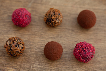 Variety of Belgian pralines from above on the wooden background. low key technique chocolate truffles on textured wooden background