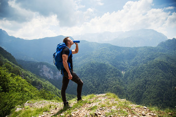 Thirsty and tired male hiker drinking water from the bottle 