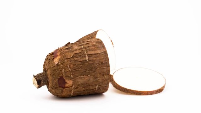 Two yuca tuber halves with cassava slices. Slowly rotating on the turntable. Isolated on the white background. Close-up. Macro.