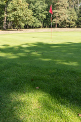 Obraz premium Flag with a mast on a golf course in a hole.