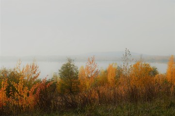 Morning mood in autumn on the water with fog, lake and colorful foliage at the trees