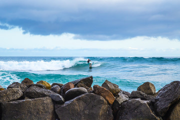 Young male person surfing on a stormy day in the atlantic ocean