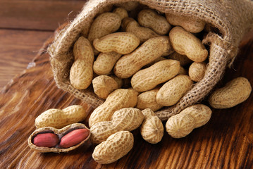 Peanuts in a peel in a bag on a wooden background.