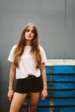 An attractive young woman wearing shorts and T-shirt amongst concrete structures in a city
