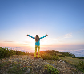 Woman expressing her inner joy in majestic landscape during sunset