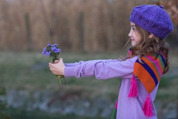 Little cute little girl holding bouquet of flowers. Child giving flowers
