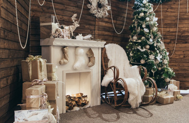 Christmas photo zone, decor. Cozy Christmas decorations. Christmas tree, fireplace, many gifts, rocking chair, lights. Cozy holiday photo. New Year's photo zone