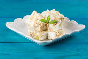 Italian torrone or nougat with almonds and pistachios from Apulia, traditional christmas sweets on blue background