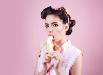 pretty girl in vintage style. pinup girl with fashion hair. banana dieting. pin up woman with trendy makeup. retro woman eating banana, copy space. Taking order on fruits
