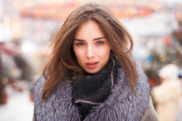 Young brunette woman in a gray coat with a fur collar