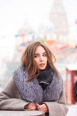 Young brunette woman in a gray coat with a fur collar