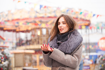 Young brunette woman in a gray coat with a fur collar