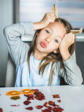 Cheeky cute blond little girl playing with dried fruit