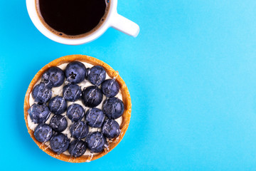 Delicious blueberry tartlet with vanilla cream and cup of coffee