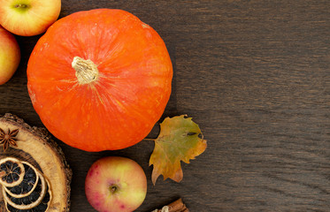 Round orange pumpkins with autumn leaf, apples and spices, flat lay on wooden background.