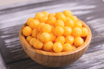 Cheese puff balls in wooden bowl on wooden background