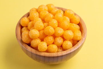 Cheese puff balls in wooden bowl on bright colorful background