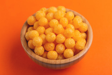Cheese puff balls in wooden bowl on bright colorful background
