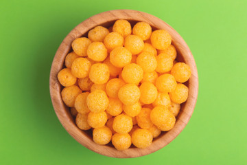 Cheese puff balls in wooden bowl on bright colorful background