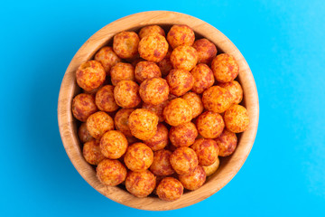 Bacon puff balls in wooden bowl on bright colorful background