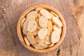 Wheat salted crackers in wooden bowl on burlap napkin