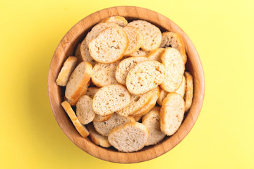 Wheat salted crackers in wooden bowl on bright colored background