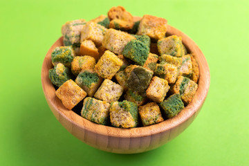Spinach flavored crackers in wooden bowl on bright colored background