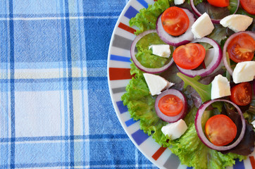 Tomato salad with lettuce, feta cheese and mustard and garlic dressing. Top view