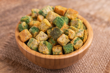 Spinach flavored crackers in wooden bowl on burlap napkin