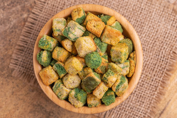 Spinach flavored crackers in wooden bowl on burlap napkin