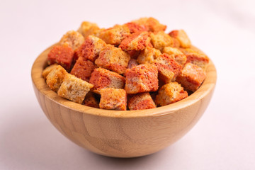 Bacon flavored crackers in wooden bowl on light marble background