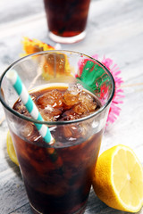 Softdrink with ice cubes, lemon and straw in glass