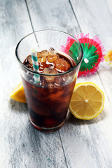 Softdrink with ice cubes, lemon and straw in glass
