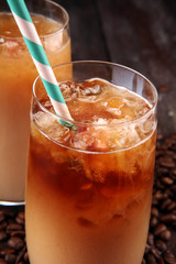 Ice coffee on a rustic table with cream being poured into it showing the texture and refreshing look of the drink