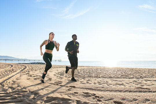 Sportive couple running on the beach.