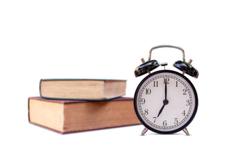 Black retro alarm clock at 07:10 o'clock   old book as background.with space for text