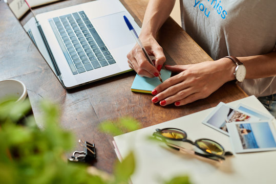 Woman taking notes while working with laptop