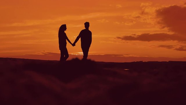 Silhouette of couple walking on beach at sunset holding hands. happy man and girl on seashore in the lights of sunset. concept romance love lifestyle friendship