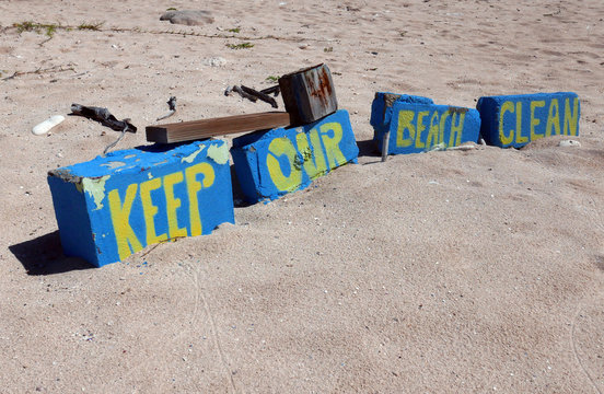 Sign Keep our Beach clean in yellow letters stenciled on blue bricks