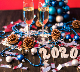 Composition with Christmas and New Year 2020 decorations and two champagne glasses, on bright background