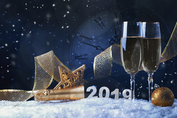 Glasses with champagne against vintage clock close to midnight